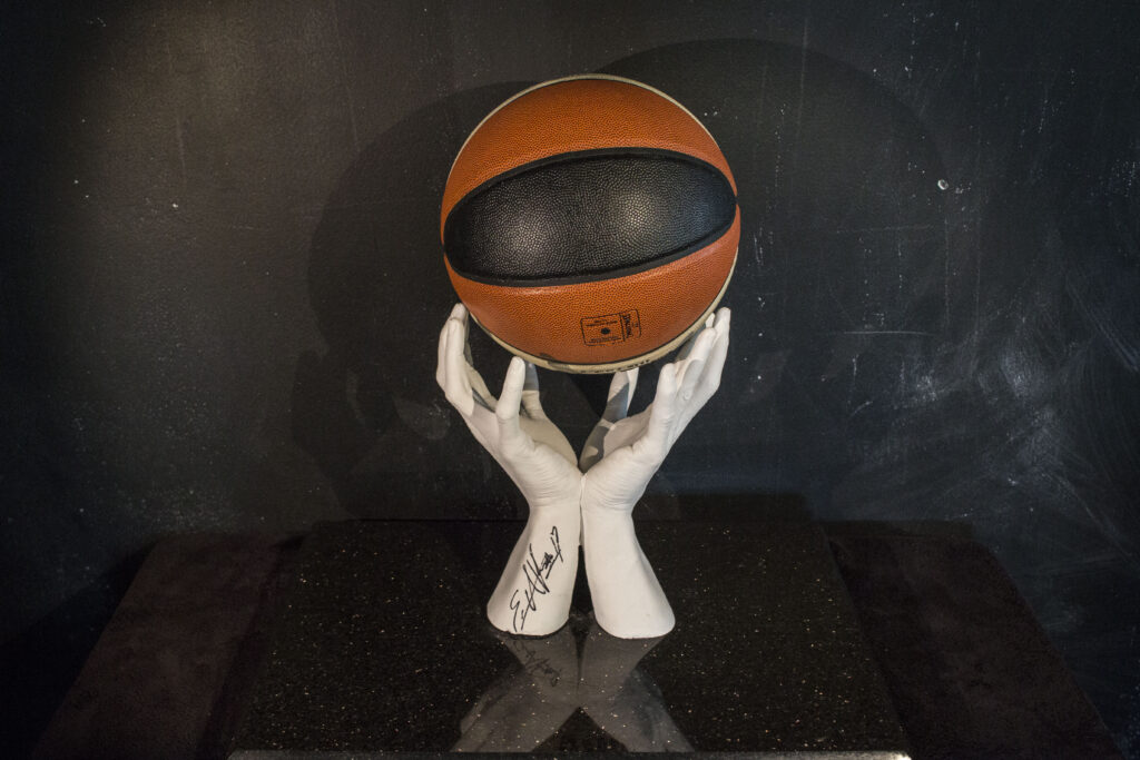 Hand-sculpted basketball-themed artwork featuring lifelike hands holding a signed basketball, crafted with precision and artistry.