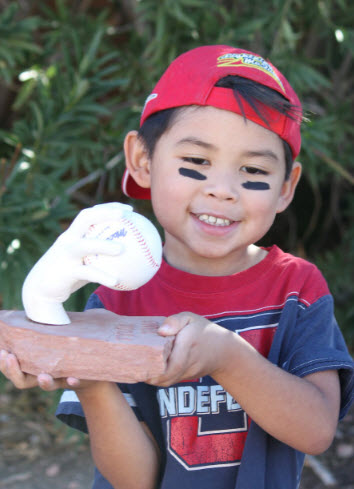 A young boy proudly holding a hand-cast sculpture of a baseball grip, symbolizing the emotional value of capturing a first home run memory.